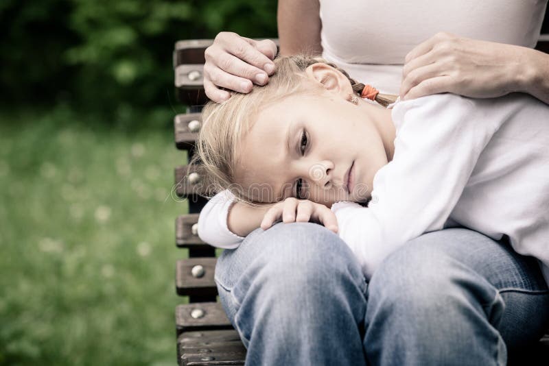 Sad mother and daughter sitting on bench in the park. At the day time royalty free stock images