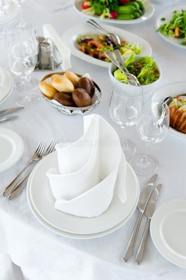 Served table seat in bright colors with a beautifully laid out napkin and salads in background royalty free stock image