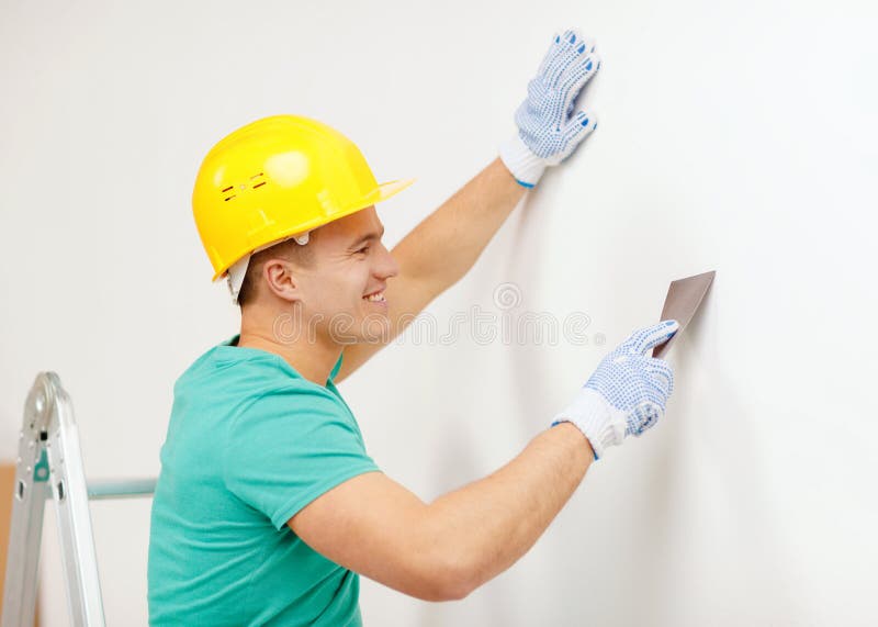 Smiling man in helmet doing renovations at home. Repair, renovation and home concept - smiling man in helmet doing renovations at home royalty free stock images