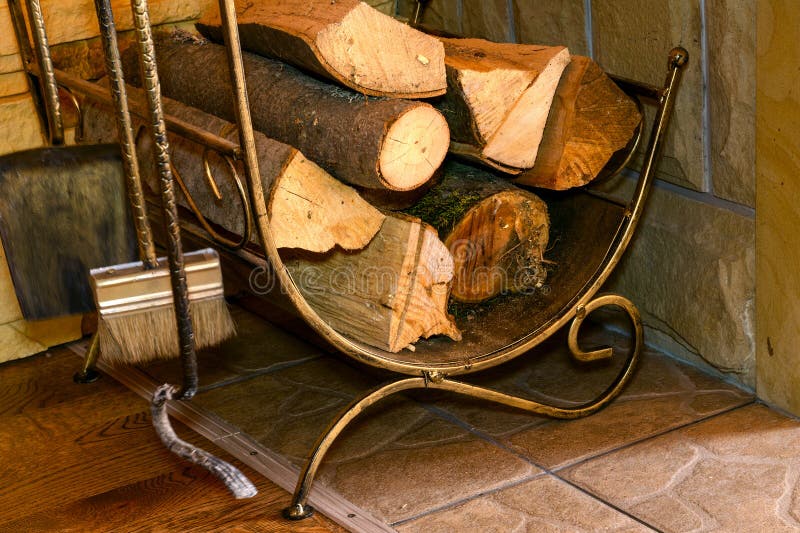 Stack of dry firewood, and fireplace accessories stand near house wall. royalty free stock image