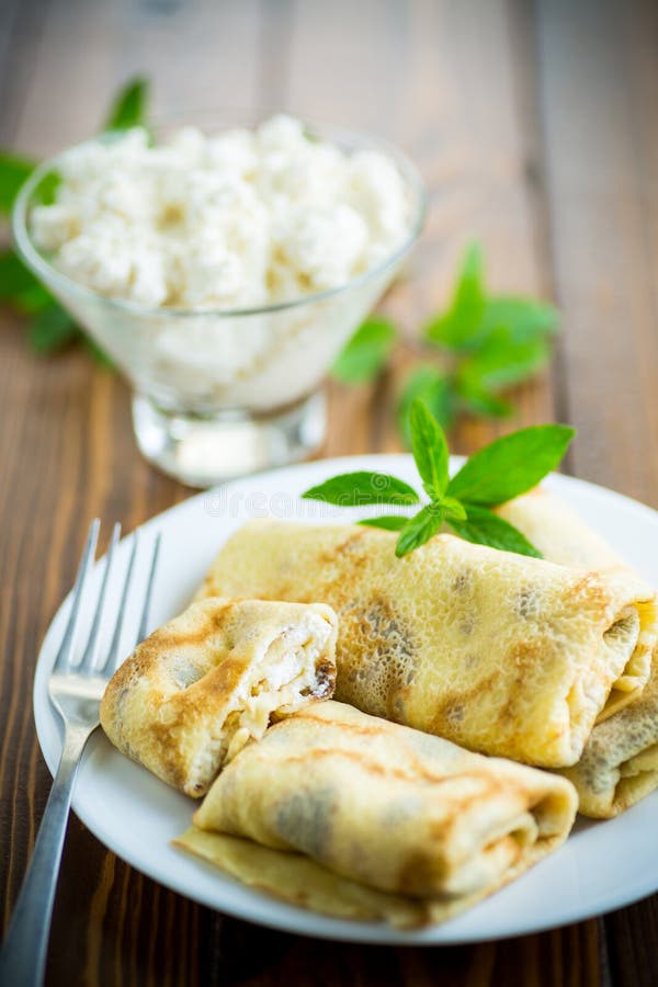 Sweet fried thin pancakes with cottage cheese inside. On a wooden table royalty free stock images
