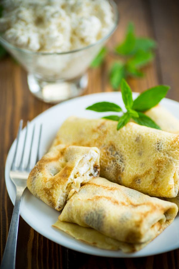 Sweet fried thin pancakes with cottage cheese inside. On a wooden table royalty free stock image