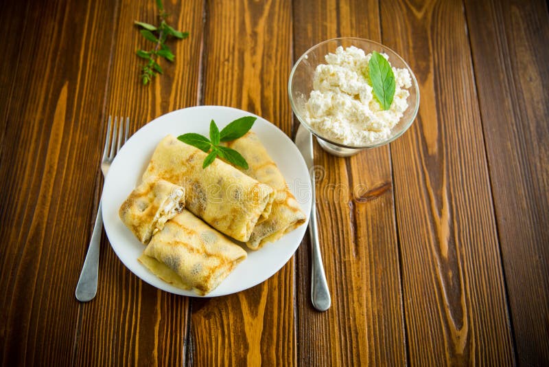 Sweet fried thin pancakes with cottage cheese inside. On a wooden table royalty free stock photo