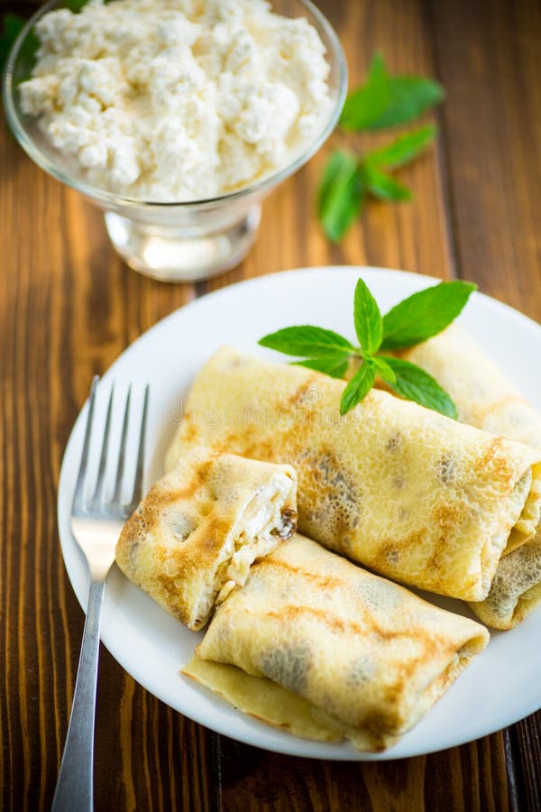 Sweet fried thin pancakes with cottage cheese inside. On a wooden table royalty free stock photography