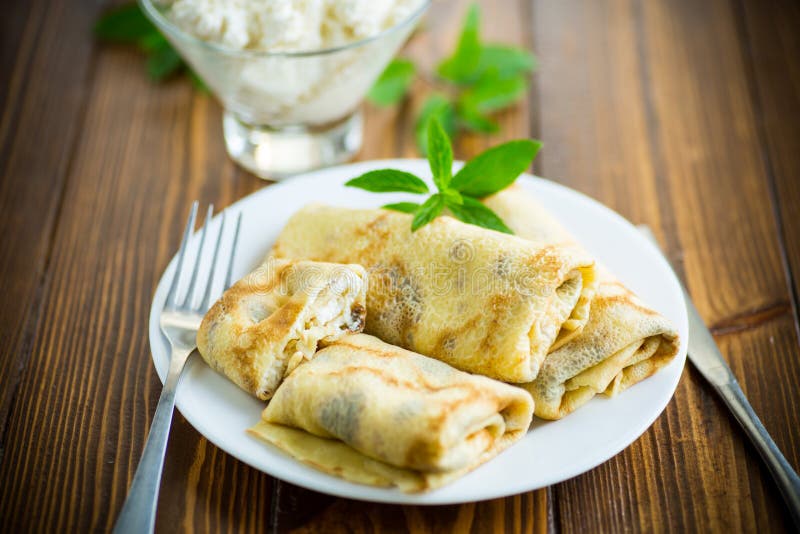 Sweet fried thin pancakes with cottage cheese inside. On a wooden table stock photos