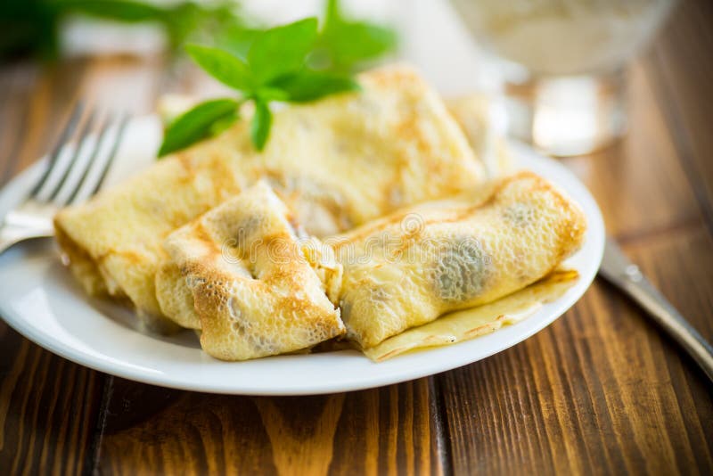 Sweet fried thin pancakes with cottage cheese inside. On a wooden table royalty free stock images