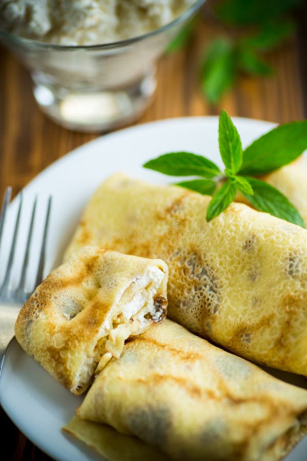 Sweet fried thin pancakes with cottage cheese inside. On a wooden table royalty free stock photography