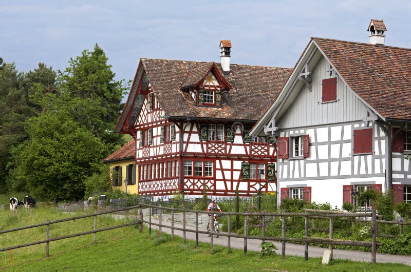 Swiss half-timbered houses in rural landscape. Typical houses in Swiserland. One home with painted windows and blow bottom of roof, gutter and a garden full of royalty free stock image