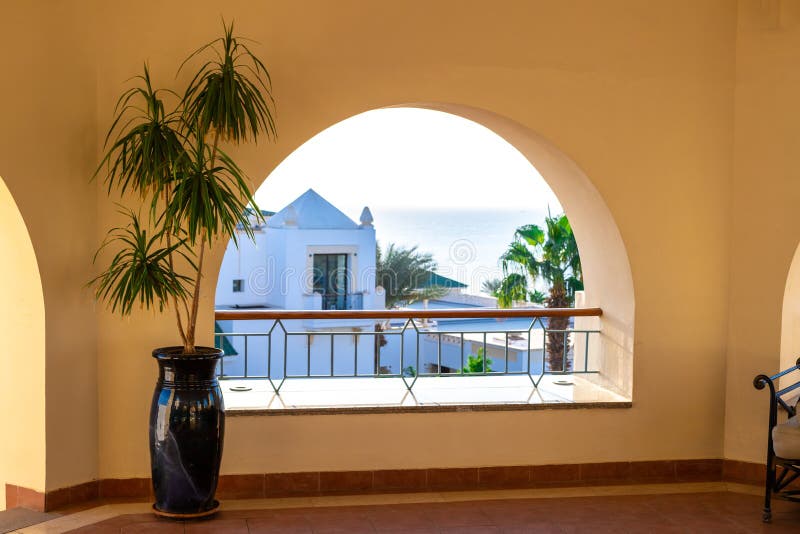 Terrace with arch overlooking the sea. Tall plant in a pot on a spacious balcony. A semicircular window overlooking the villa and. Terrace with arch overlooking stock photography