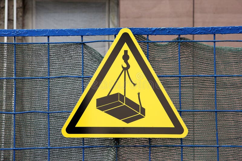 Traffic construction yellow triangular sign warning about falling weigh from height on construction site stock photography