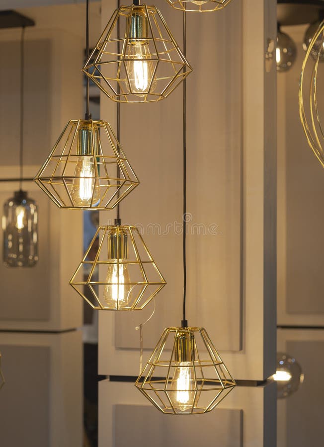 Trendy golden geometric pendant lamp with a bulb  hanging in the chandelier shop. Trendy golde metal geometric pendant lamp with a bulb  hanging in the stock photo