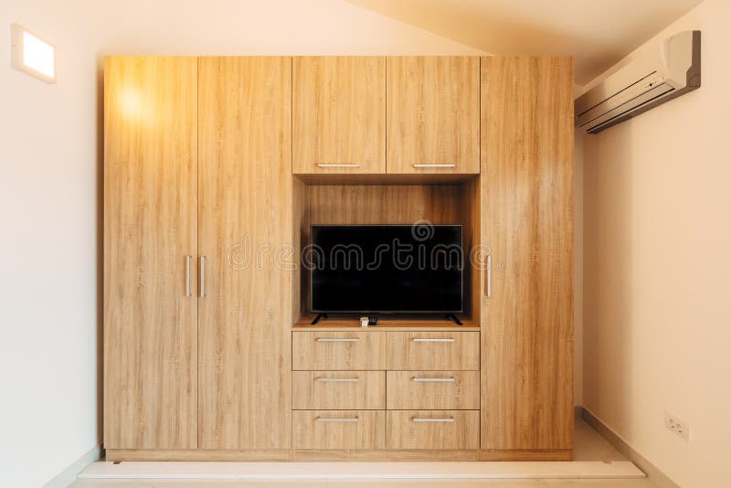 TV set in a niche in a large wooden cabinet in a bright air-conditioned room. stock image