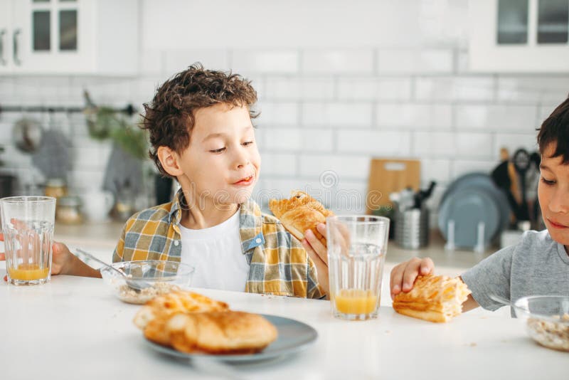 Two siblings tween boys real brothers having breakfast on bright kitchen at home royalty free stock images