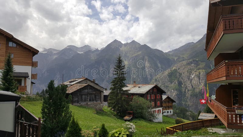 Typical Swiss village with wooden houses on top of the slope of the rugged alpine mountains.  royalty free stock photos