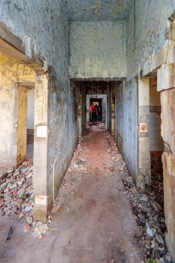 Vertical shot of a group of tourists walking in along a hallway inside a destroyed historic building stock photos