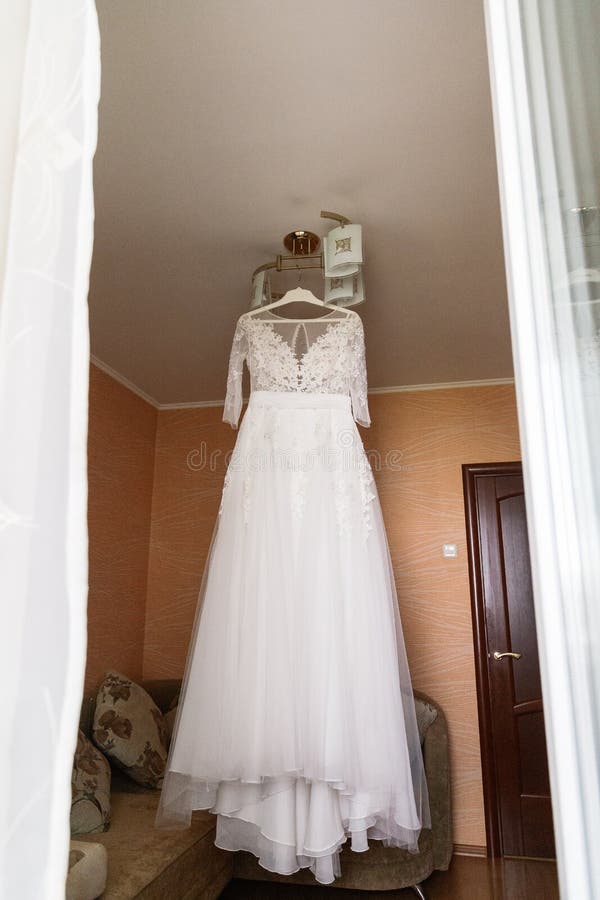 Very beautiful wedding dress of the bride hanging on the chandelier in the room. Very beautiful wedding dress of the bride hanging on the chandelier in the room royalty free stock image