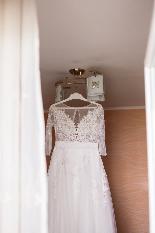 Very beautiful wedding dress of the bride hanging on the chandelier in the room. Very beautiful wedding dress of the bride hanging on the chandelier in the room royalty free stock photography