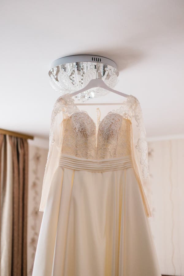 Very beautiful wedding dress of the bride hanging on the chandelier in the room. Very beautiful wedding dress of the bride hanging on the chandelier in the room royalty free stock photos
