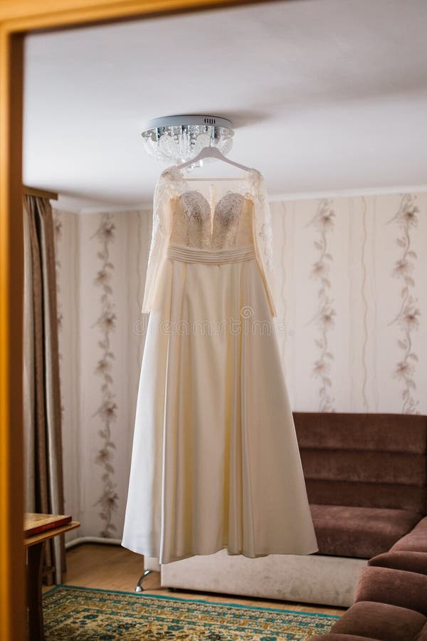 Very beautiful wedding dress of the bride hanging on the chandelier in the room. Very beautiful wedding dress of the bride hanging on the chandelier in the room stock photos