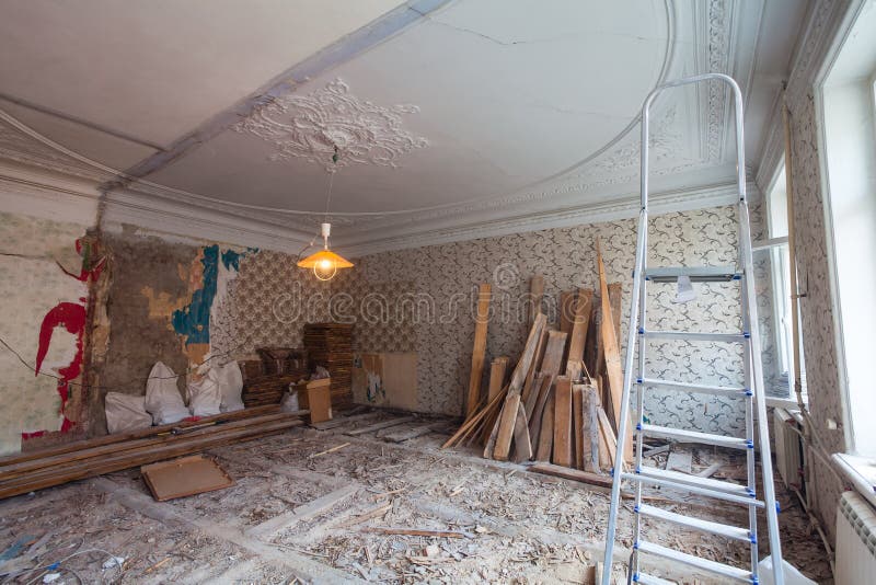 View the vintage room with fretwork on the ceiling of the apartment during under renovation, remodeling and construction. Ladder, garbage of contraction stock photo