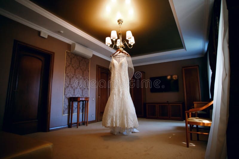 Wedding dress hanging on a chandelier in a hotel room, wedding day, beautiful, modern dress. Holiday atmosphere royalty free stock photos