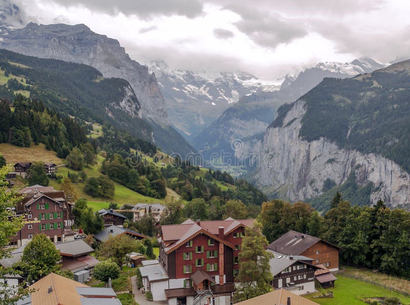 Wengen in the swiss Alps. In a valley with rural houses, in the background are mountains on a cloudy day stock image