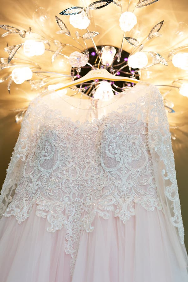 White bride dress hanging on a chandelier in the room.  stock photos