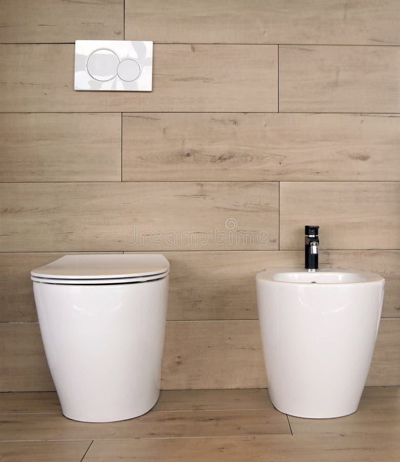 White ceramic toilet and bidet in   a bathroom made of stoneware with wood effect royalty free stock photos
