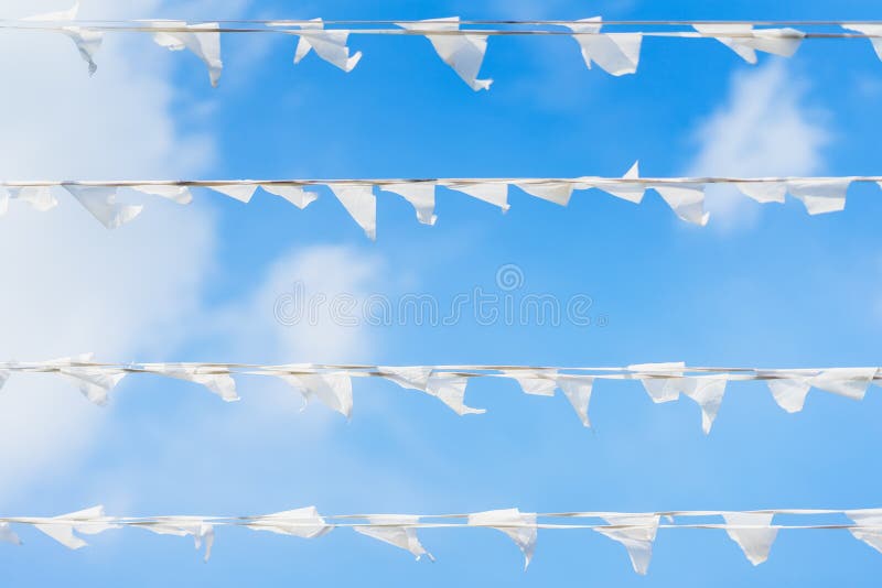 White flags of triangular shape, pennants against blue cloudy sky in horizontal garland. City street holiday, Festival stock photo