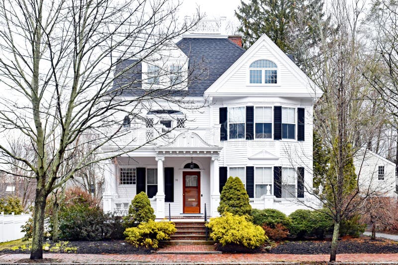 White Historic House with Wood Door and Unique Windows. Historic house. White with wood door and black shutters. Mature landscaping. Brick sidewalk. Unique royalty free stock images