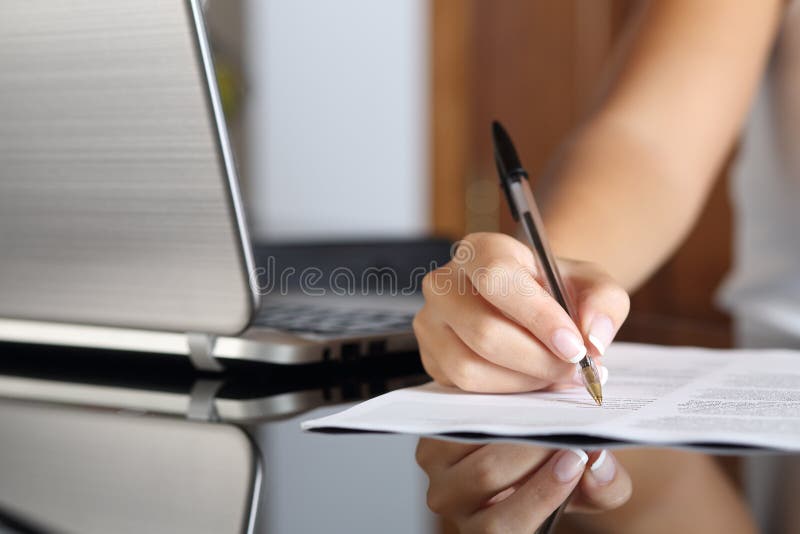Woman hand writing a contract with a laptop beside royalty free stock images