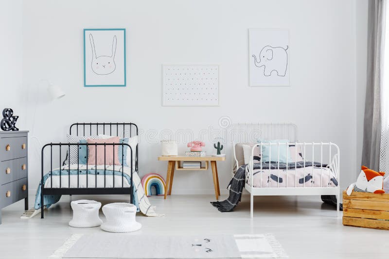 Wooden table between black and white bed in children bedroom int stock photography