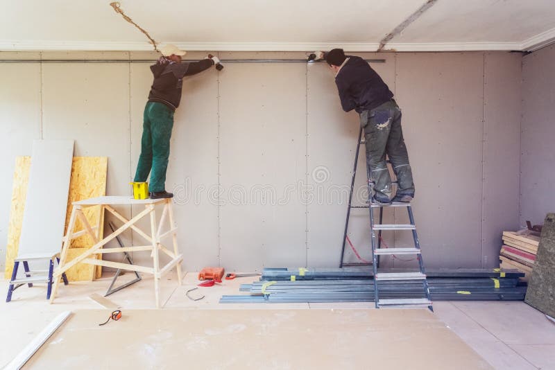 Workers are installing plasterboard drywall for gypsum walls in apartment is under construction, remodeling, renovation. Extension, restoration and stock photography