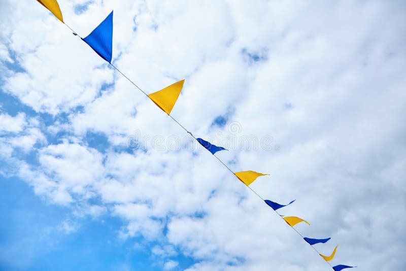 Yellow and blue triangular festival flags on sky background with white clouds. Outdoor Celebration Party. Festive royalty free stock images