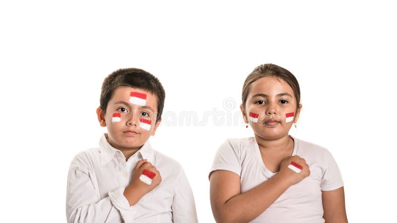 Young boy and girl with hands over their hearts while wearing face paint of their national flag, Indonesia stock photo