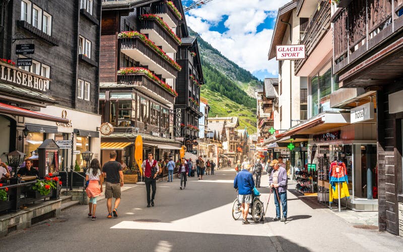 Zermatt Bahnhofstrasse Main shopping street full of people with old Swiss wooden houses and dramatic light during summer 2020 in. Zermatt Switzerland , 2 July royalty free stock photo