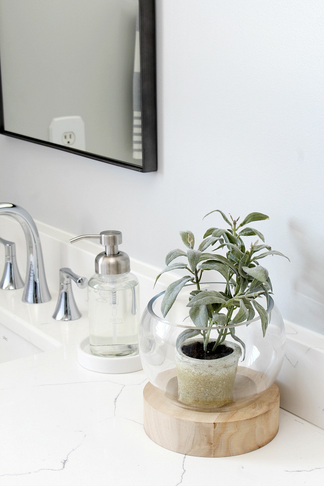 Glass and wood plant holder in a coastal style bathroom.