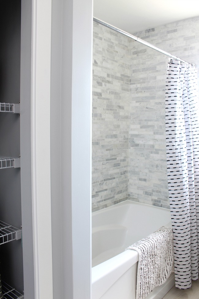 Bathroom makeover with a bath/shower combo with marble tiles.