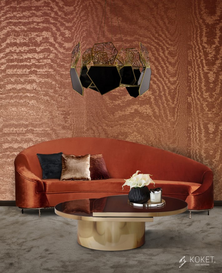 A room with orange moire wallpaper, an orange curved sofa by koket, and a tears koktail table by koket with a black and gold chandelier hypntocic by koket - room colors and moods - orange psychology